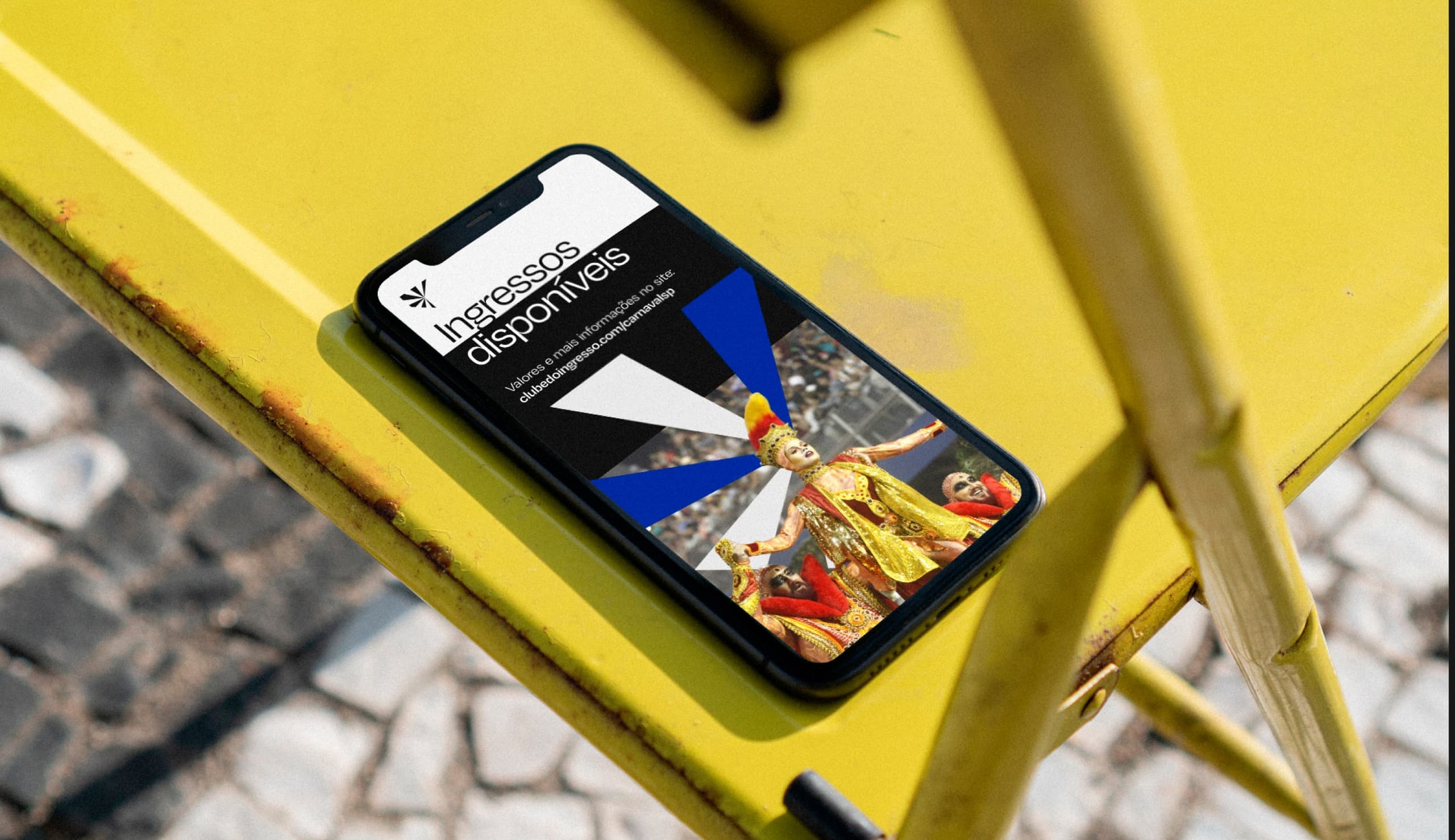 Celular com post de ingressos disponíveis sobre cadeira amarela